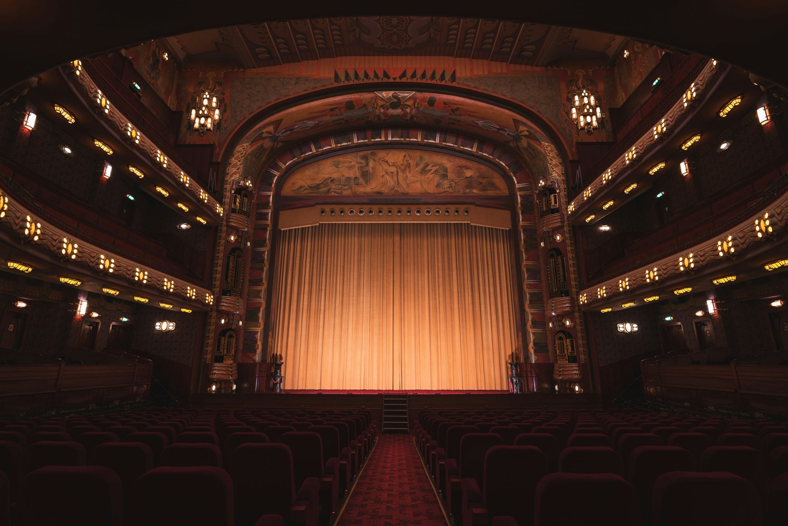 Image: Interior view of a world class theatre with low lighting and curtains drawn, image by Liam Mcgarry via Unsplash